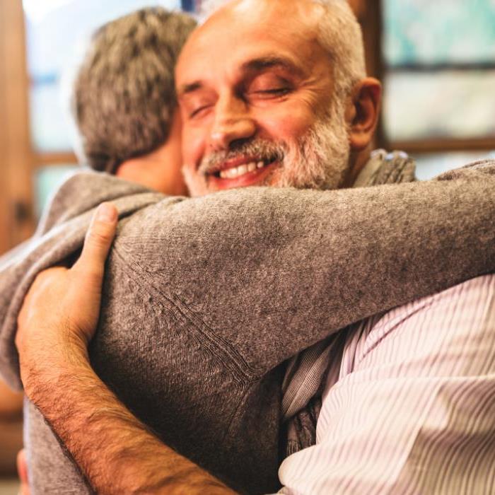 2 mensen omhelzen elkaar. De man lacht.