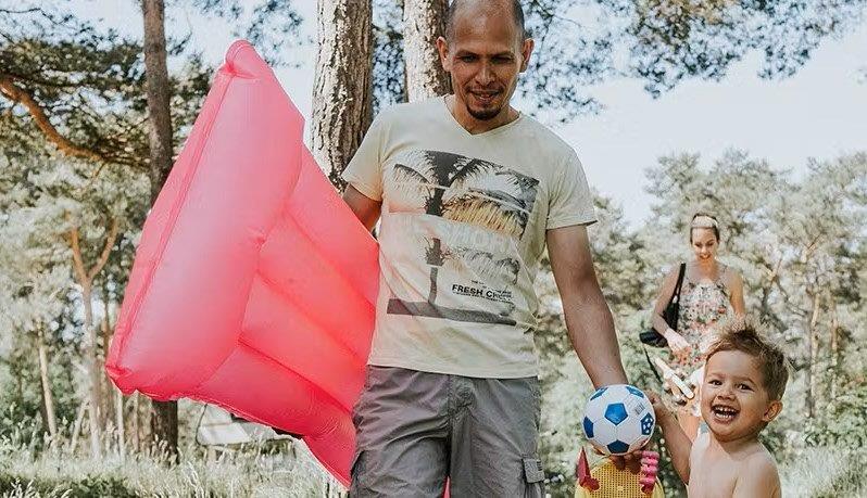 Vader en zoon gaan met het luchtbed onder de arm op pad om te gaan zwemmen