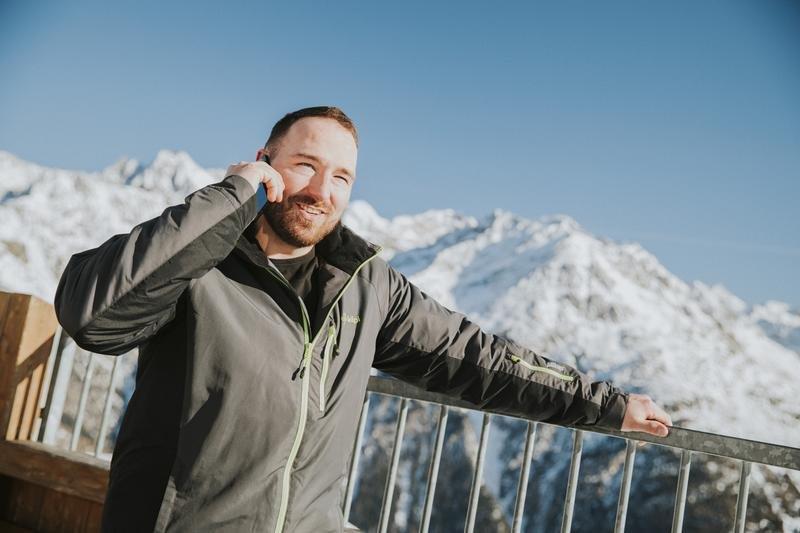 Man staat op bergtop te bellen