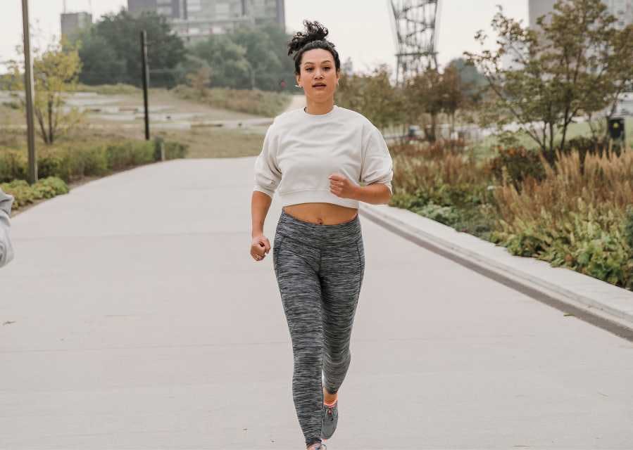 Een vrouw is aan het hardlopen in een stadspark.