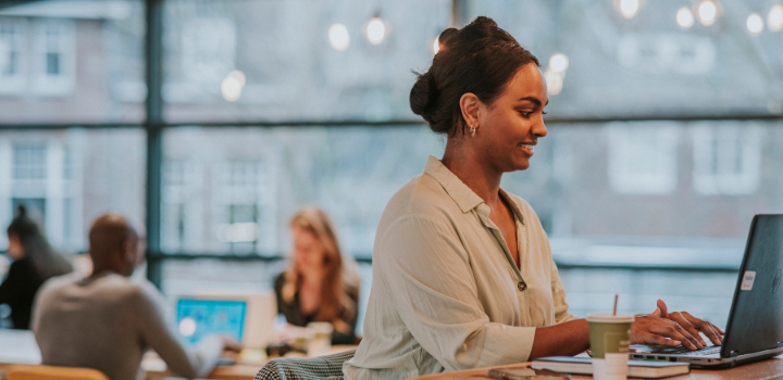 Vrouw zit achter een laptop in een kantoortuin