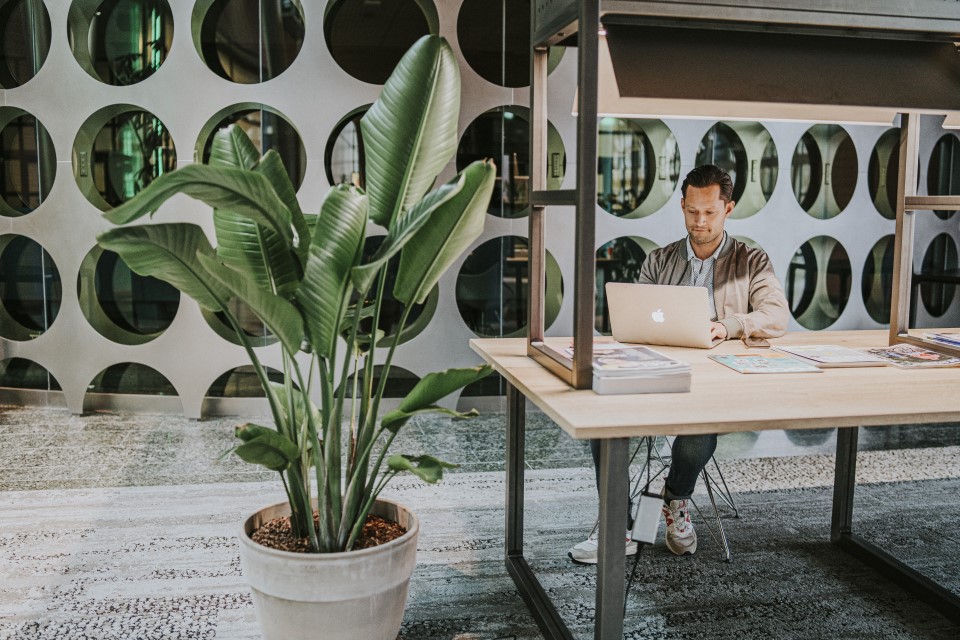 Ondernemer aan een bureau die op zijn laptop leest over het verzekeren van het risico op arbeidsongeschiktheid.