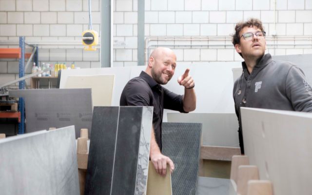 Tegelzetter Eddie staat tussen de tegel en wijst lachend ergens naar