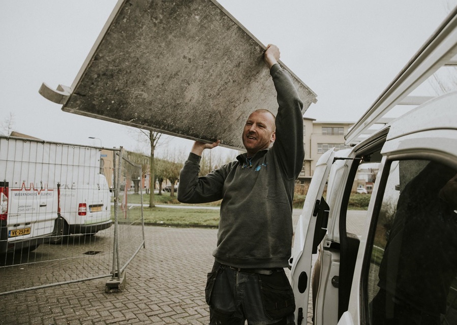 Man sjouwt een plank van een steiger. Blijf verzekerd van inkomen als je arbeidsongeschikt raakt.