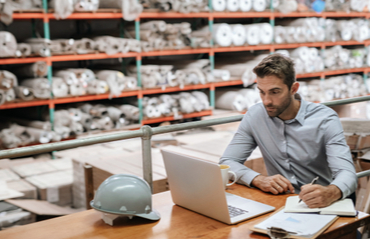 Man achter laptop in magazijn