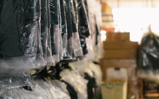 een opslagruimte met een rek met in plastic verpakte kleding