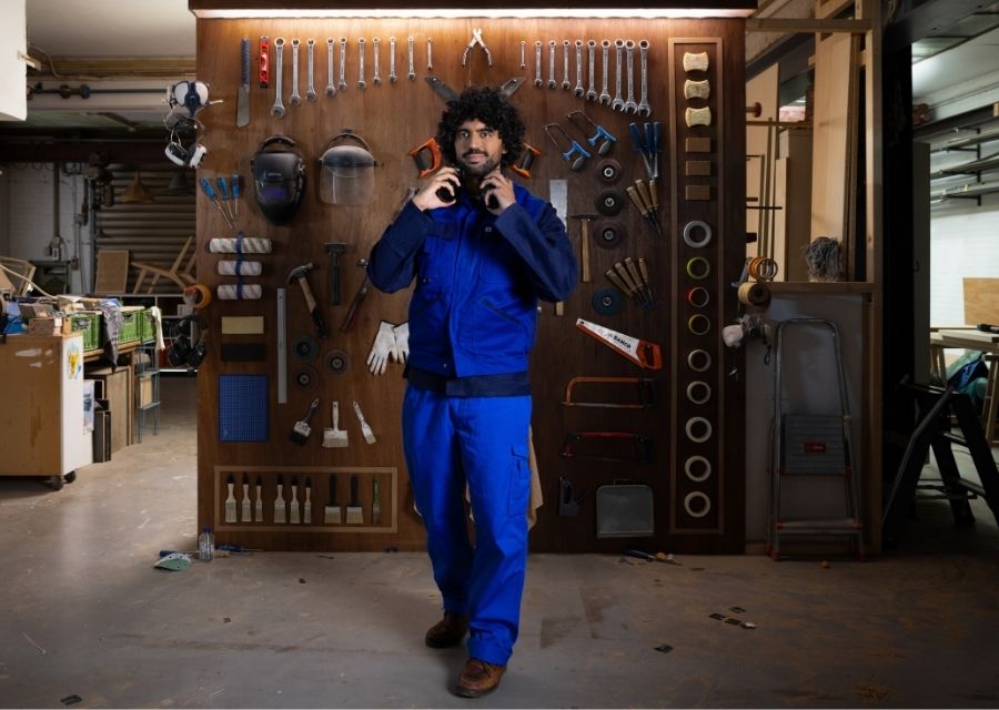 Man staat in zijn werkplaats met gereedschap op de achtergrond