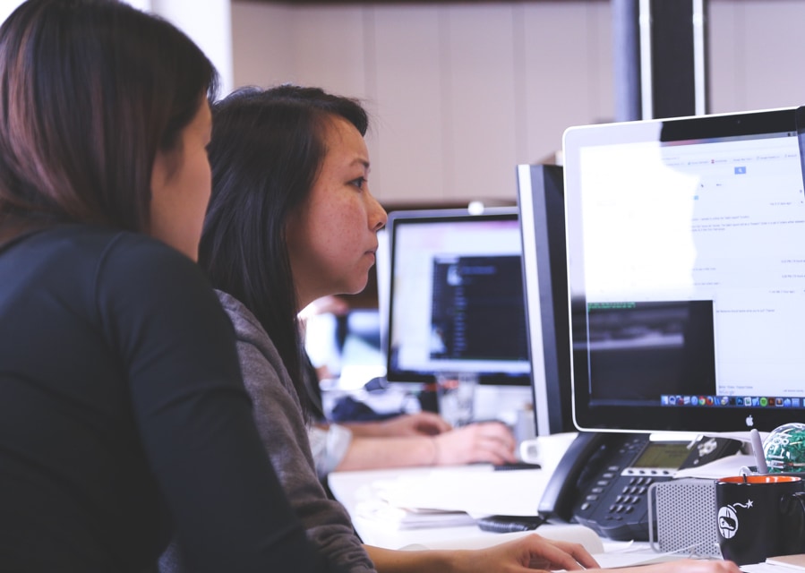 Twee vrouwen die samen aan een bureau zitten en op de computer aan het werk zijn