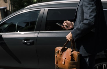 Man met tas bij een auto