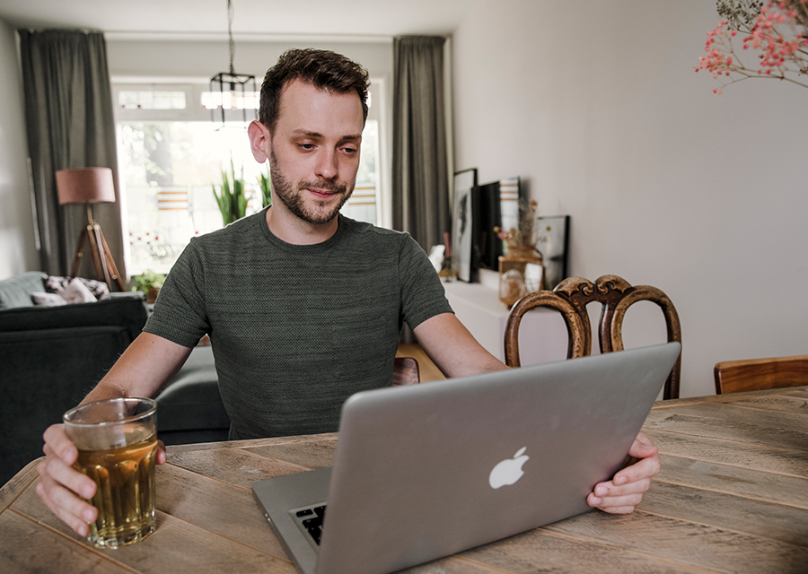 Man bekijkt thuis achter zijn laptop een video