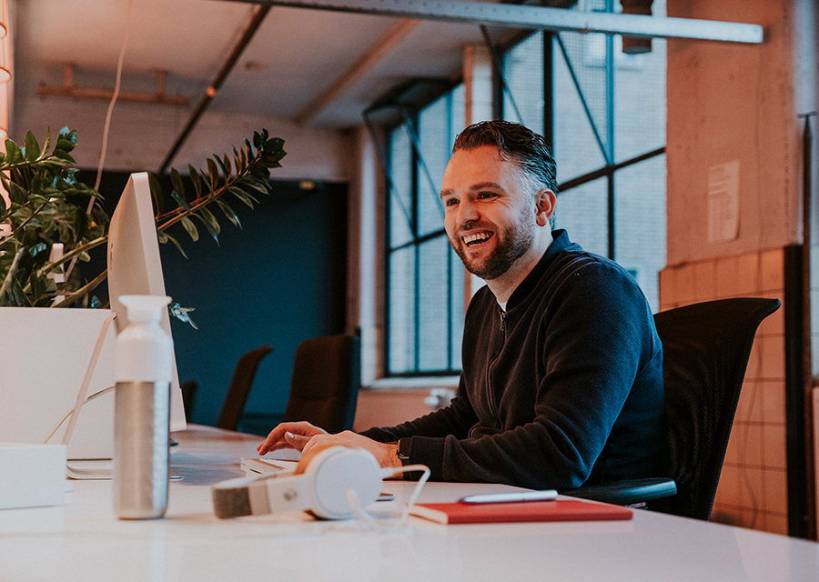 Man zit op kantoor achter zijn laptop