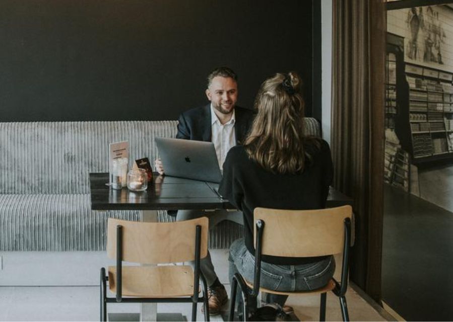 Ondernemer die met een klant aan tafel zit en in gesprek is.
