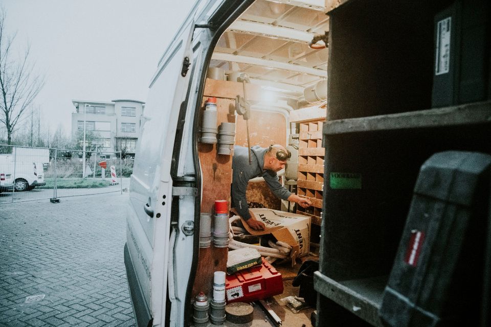 Een man zoekt onderdelen in zijn bestelauto