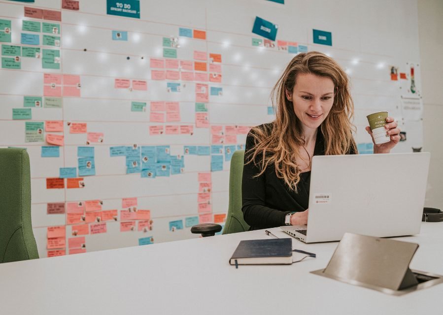 Een vrouw werkt in een kantoorruimte op haar laptop.