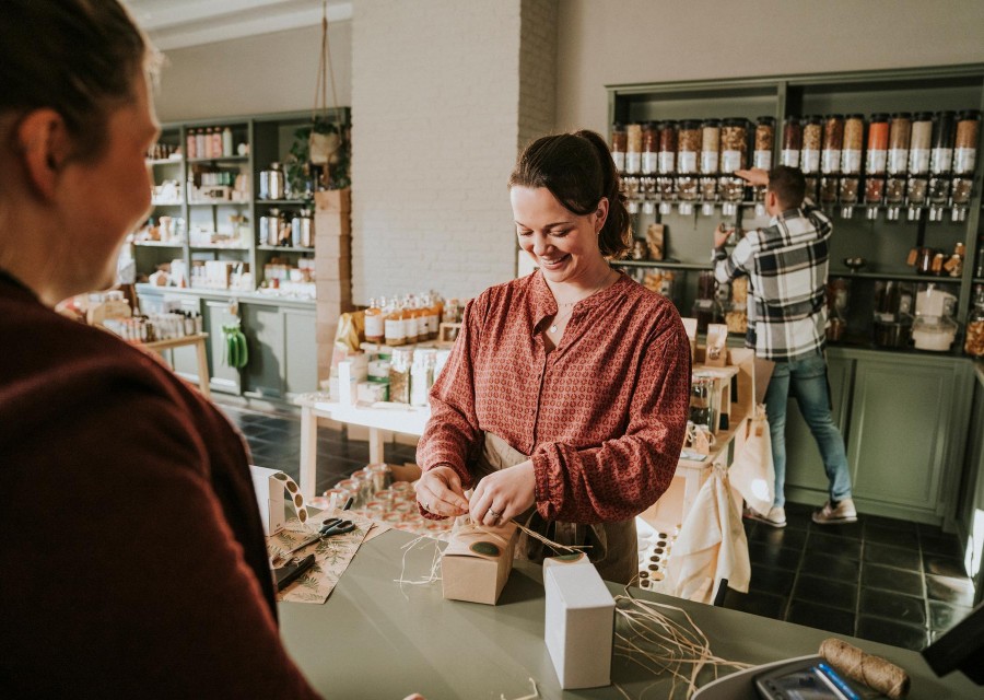 Een vrouw in een winkel pakt een cadeautje mooi in.