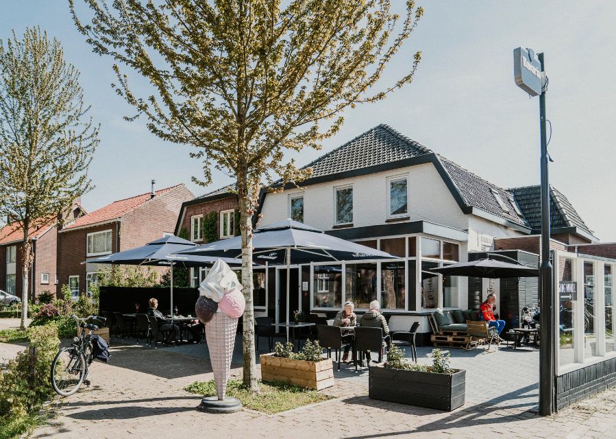 Terras van een restaurant met mensen in de zon onder parasols