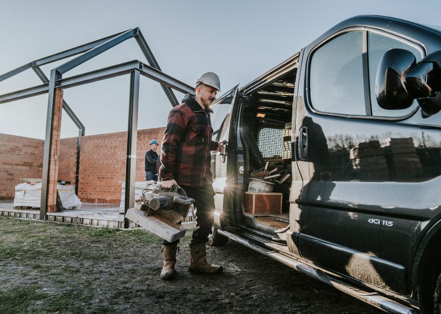 Man met helm zet gereedschap in een bestelbus