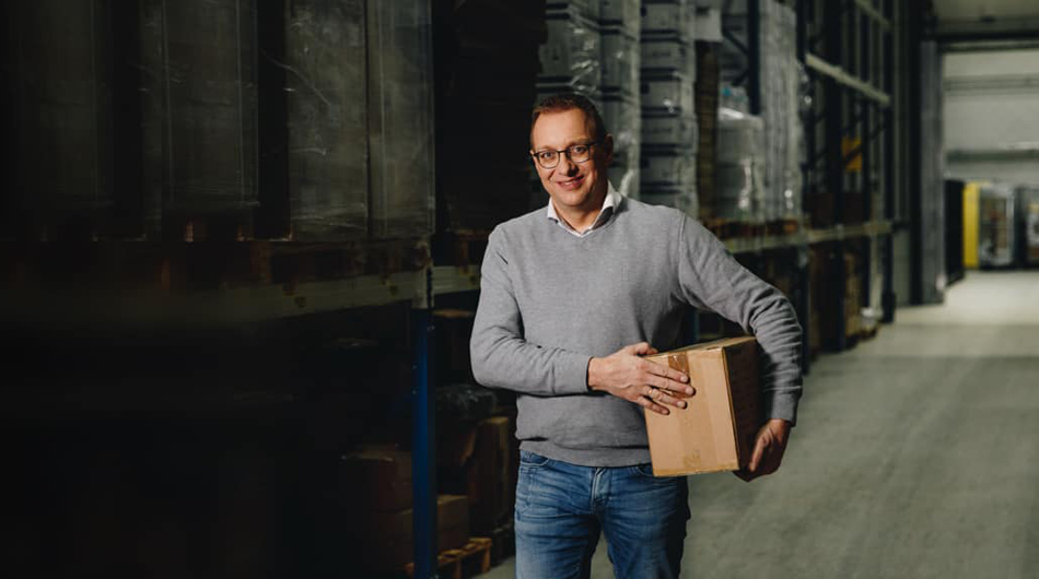 Man in een warehouse met een doos onder zijn arm