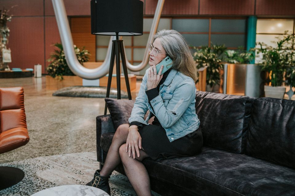 Vrouw zit op een bank in een kantoorgebouw te bellen