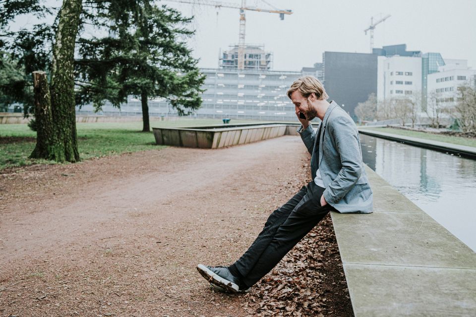Man zit op de rand van een vijer in een park 