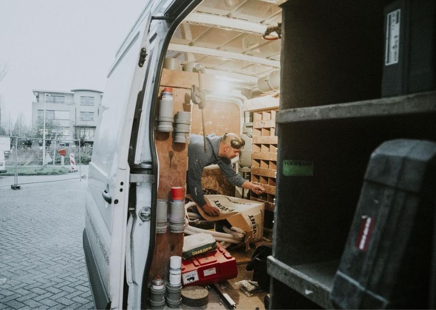 Een man is aan het werk in zijn bedrijfswagen. De zijdeur ervan is open geschoven.
