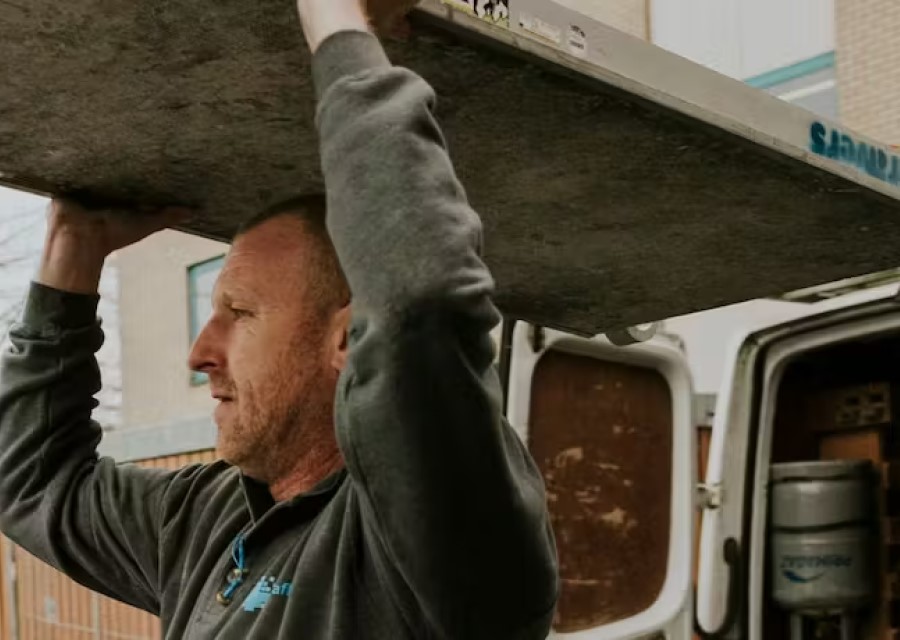 Ondernemer die bouwmaterialen uit zijn bus tilt