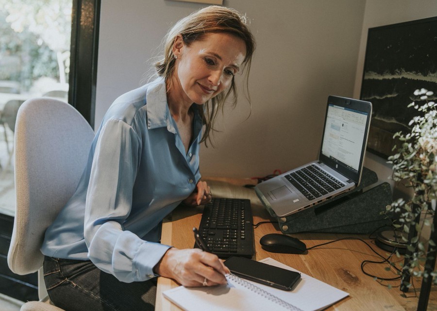 Ondernemer die aan haar bureau zit en controleert of de gegevens van haar zakelijke verzekeringen nog kloppen