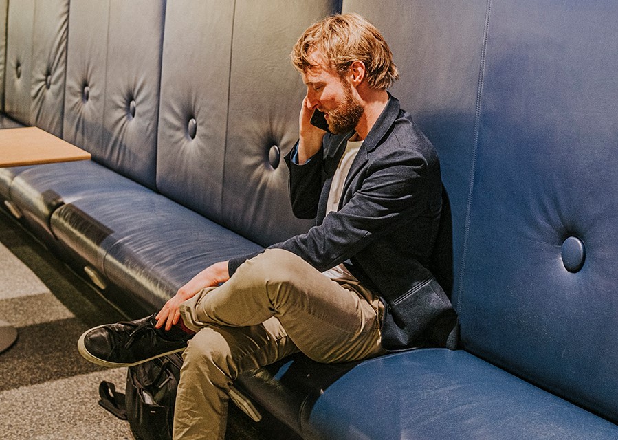 Man zit op een bankje te bellen.