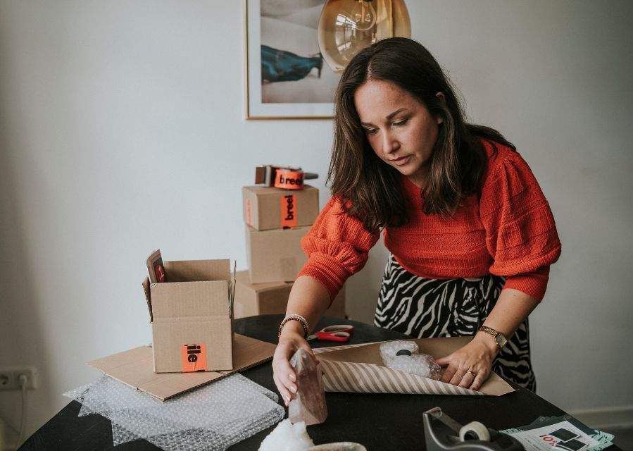 Een vrouw in bezig met het inpakken van producten om ze als pakket te kunnen verzenden.