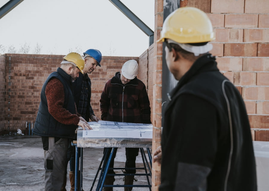 Bouwvakkers overleggen bij een bouwtekening.