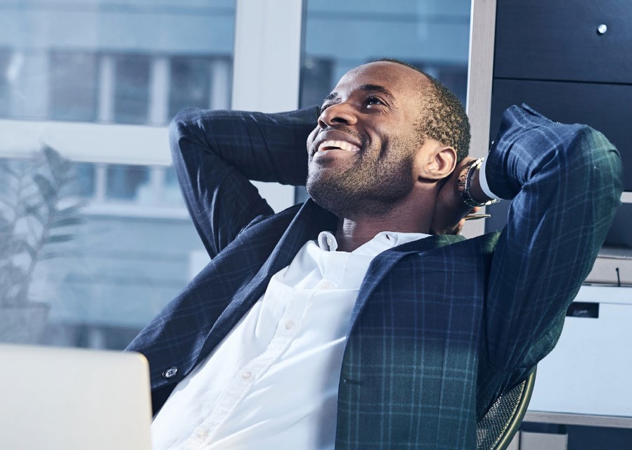 Lachende man op een bureaustoel met zijn handen achter zijn hoofd