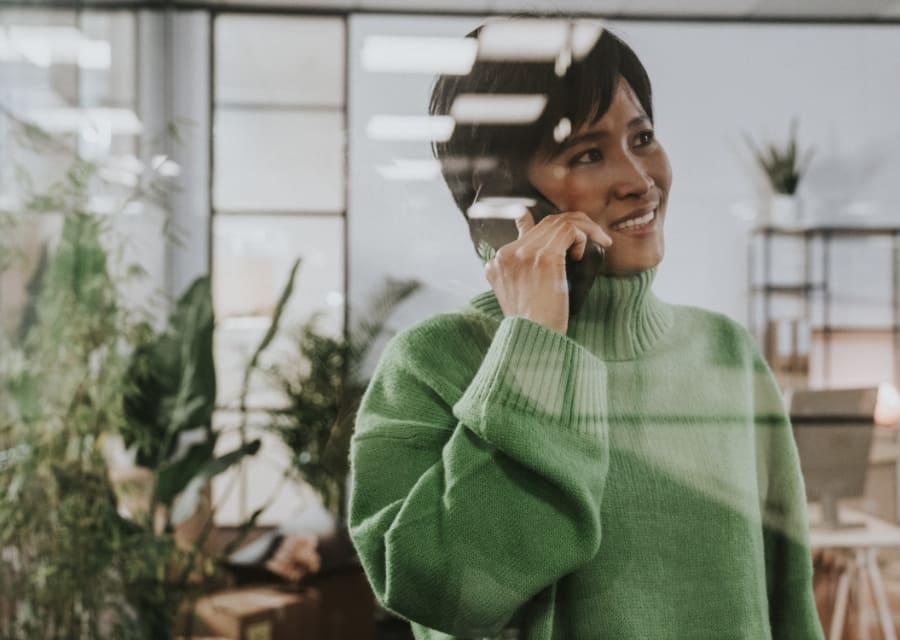 Mevrouw met een groene trui aan is aan het bellen