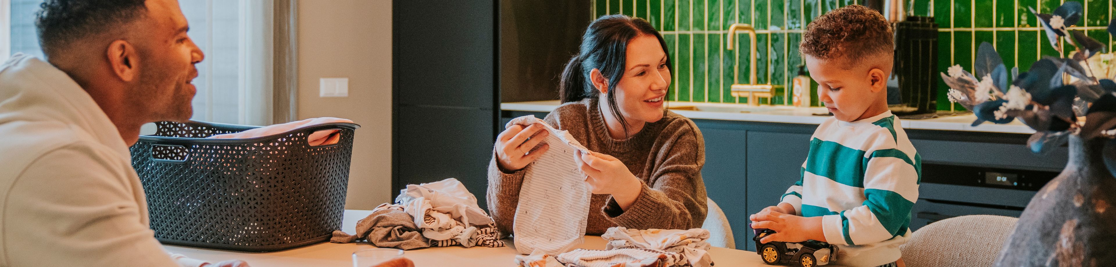 Man, vrouw en kind vouwen de was aan tafel.