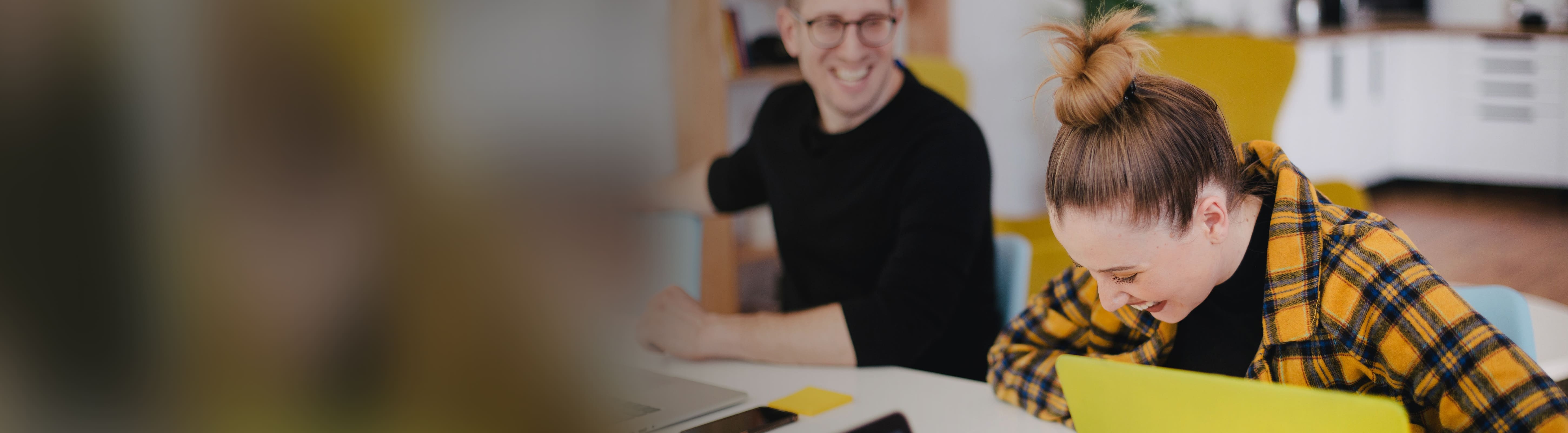 Twee jongvolwassenen die lachend aan een tafel zitten