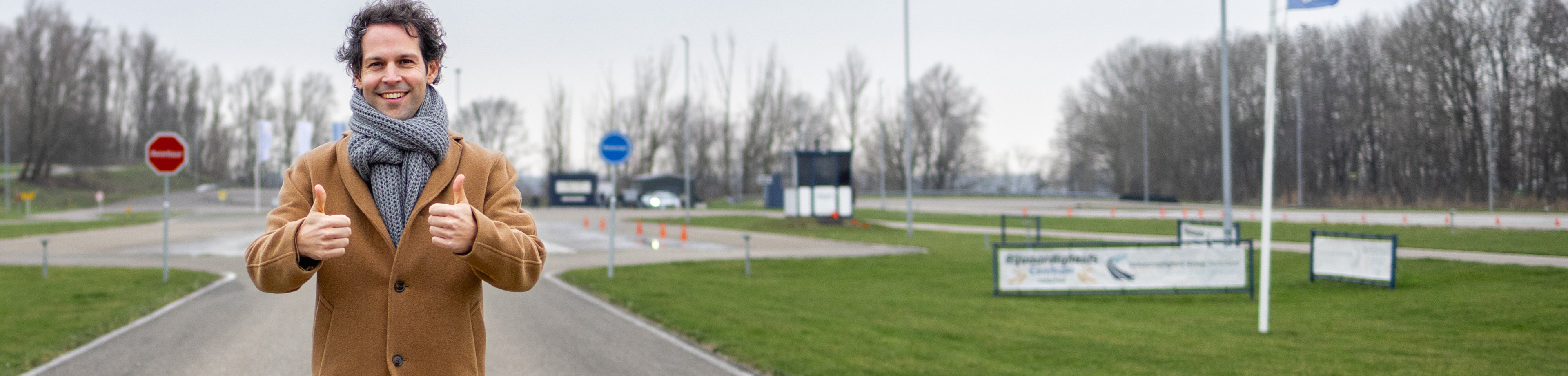 Victor Mids die op een racecircuit staan en zijn duimen opsteekt.
