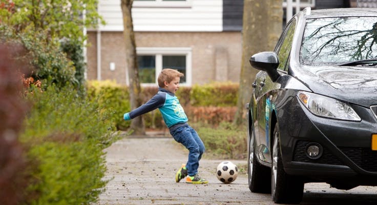 Jongetje speelt met bal bij een auto. Met de Aansprakelijkheidsverzekering van Interpolis kunt u uw aansprakelijkheid verzekeren voor schade aan anderen of schade aan spullen van anderen.