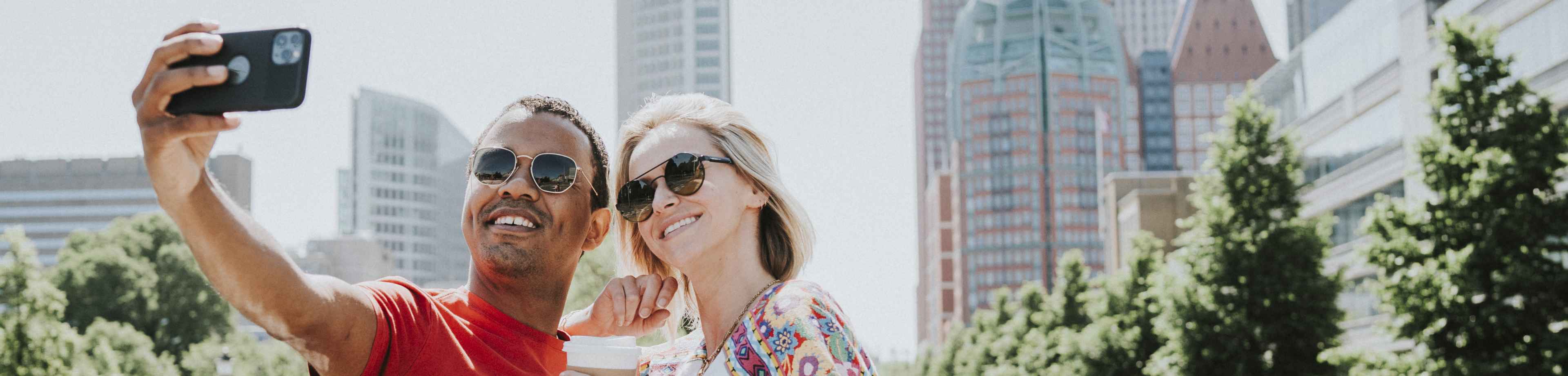 Man en vrouw die op vakantie zijn en een selfie maken. Ze sloten de doorlopende reisverzekering af met 15% korting op de premie.