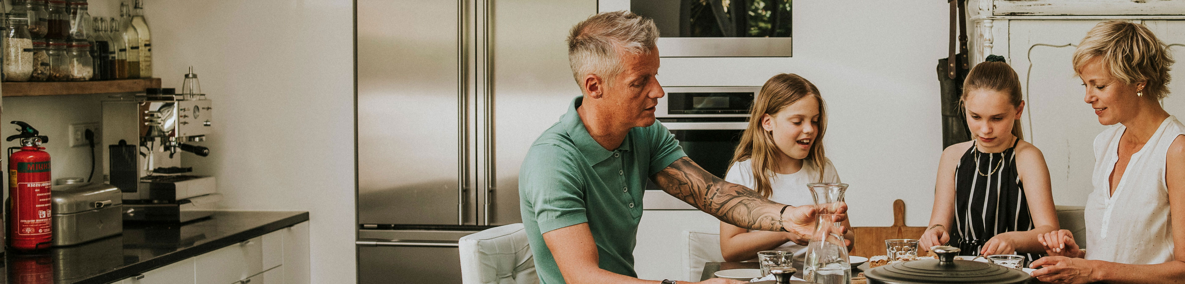 Gezin aan de keukentafel in hun huurwoning. Zij hebben een overlijdensrisicoverzekering afgesloten.