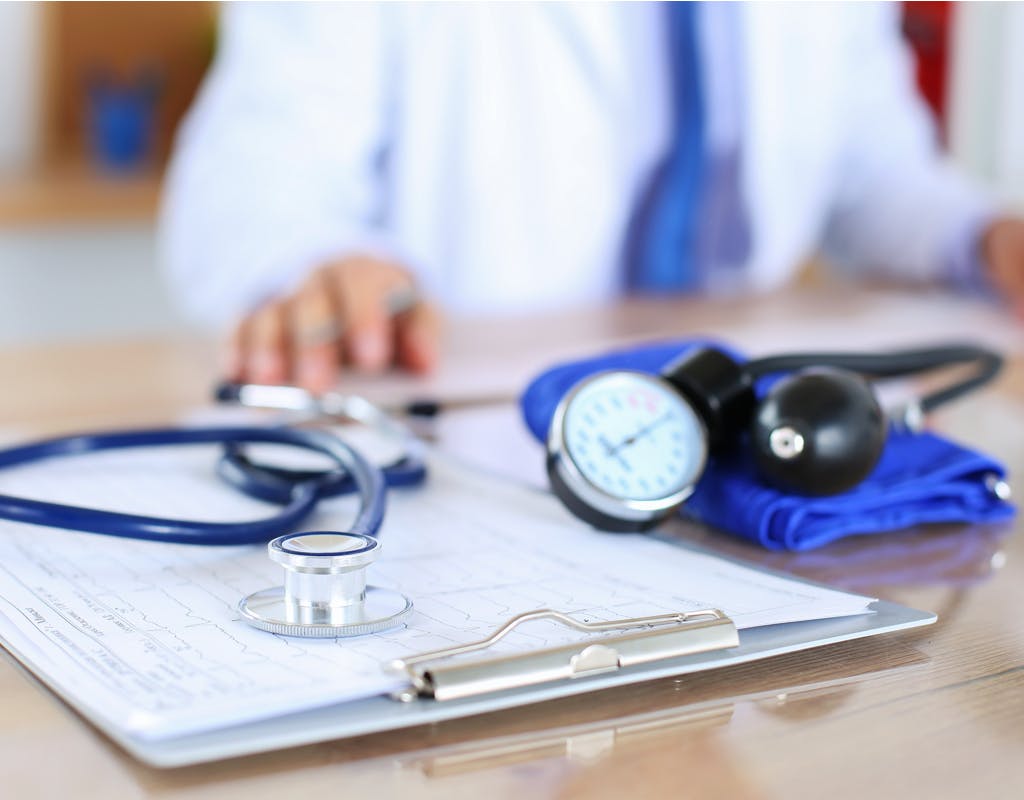 Bloeddrukmeter en stethoscoop liggen op tafel in dokterspraktijk. 
