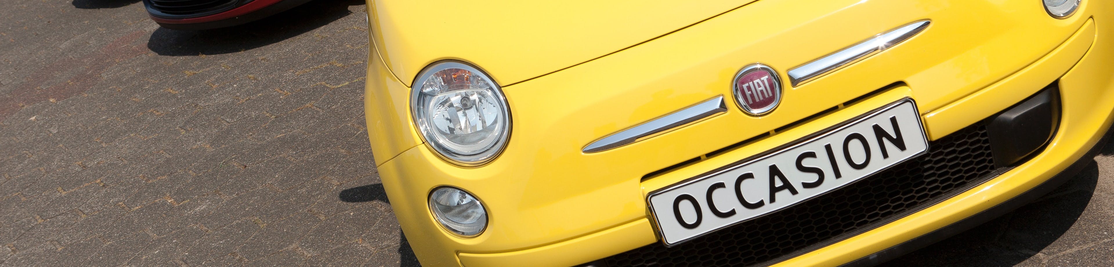 Een gele tweedehandsauto bij een autohandelaar. Met de Handelaarskentekenverzekering verzekert u, als eigenaar van een autogarage- of autohandelaarsbedrijf, schade aan of door voertuigen