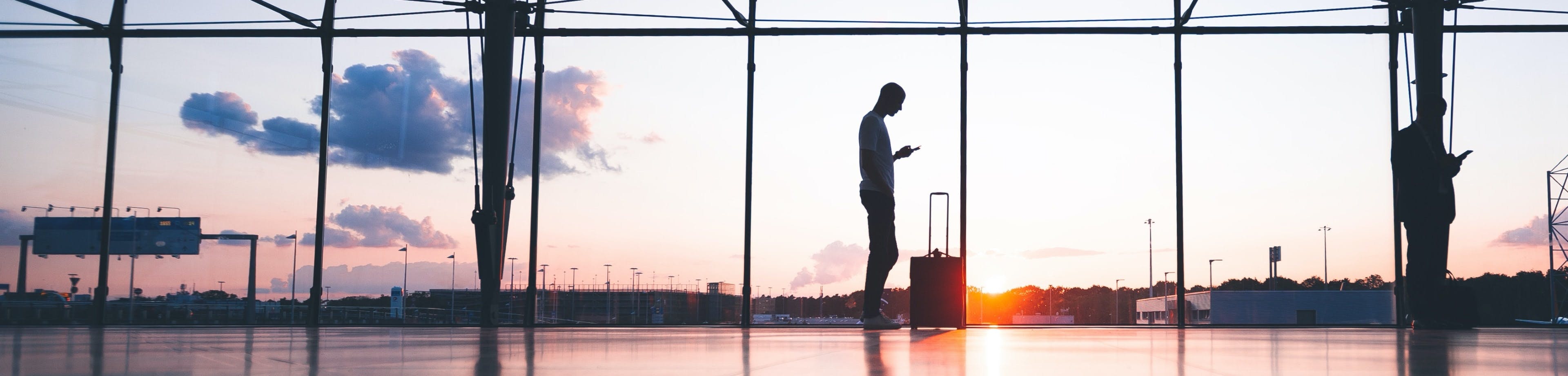 Een ondernemer staat met een reiskoffer op het vliegveld. Verzeker uw medewerkers voor personenhulp en geneeskundige kosten als zij voor het werk op reis gaan. 