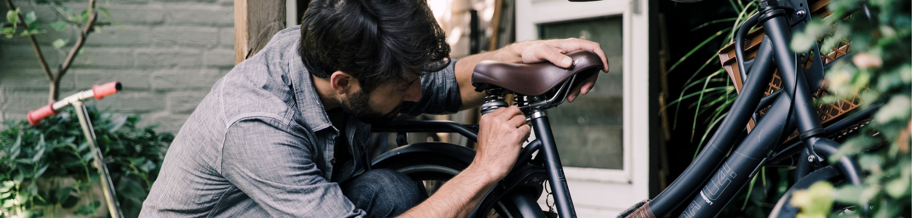 Een man is een fietszadel aan het verstellen