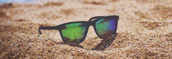 Een zonnebril die op het strandzand ligt