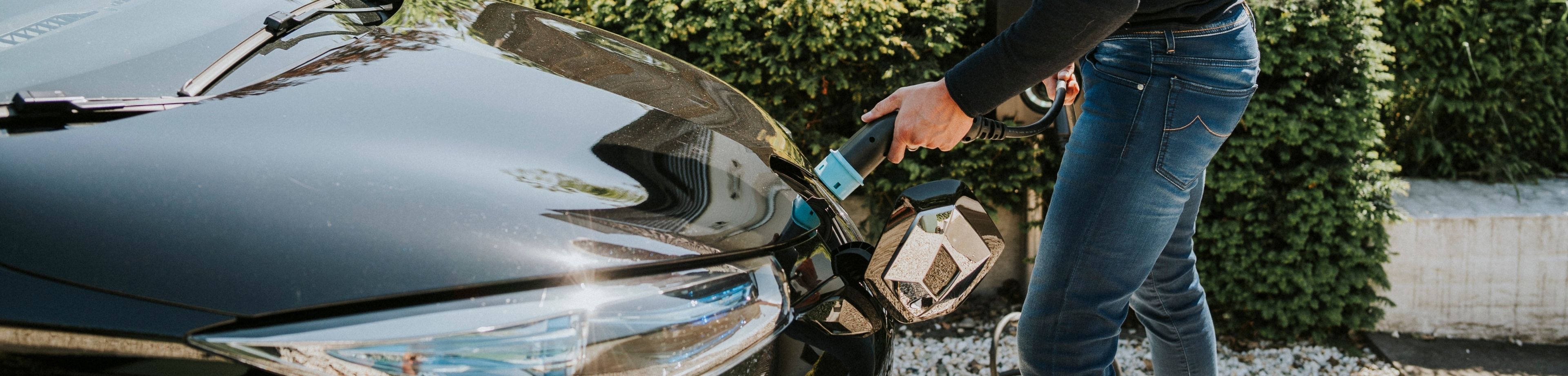 Man steekt de oplaadkabel in zijn elektrische auto