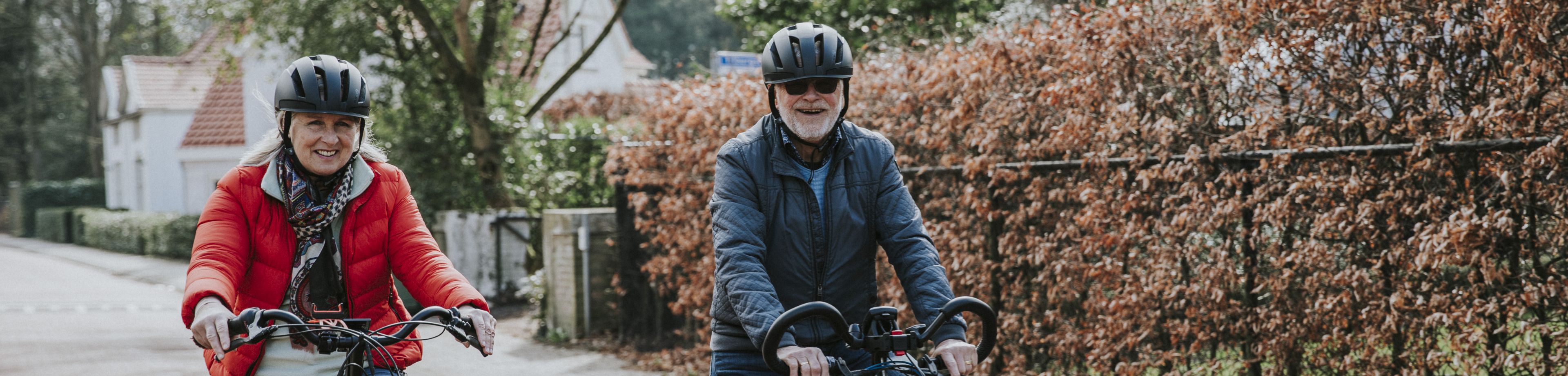 Een man en vrouw met fietshelm op fietsen op elektrische fietsen.