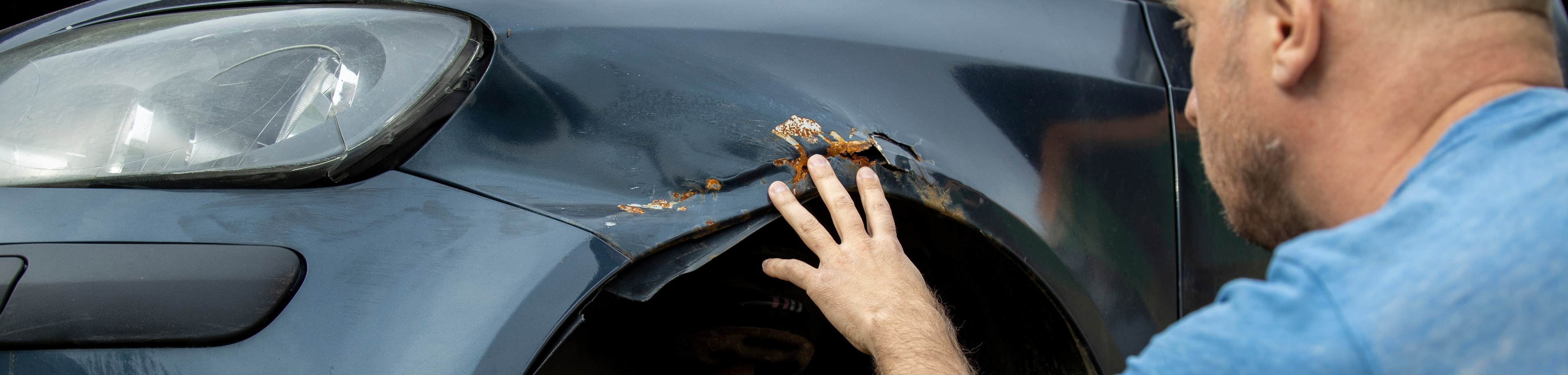Man bekijkt de schade aan zijn auto.