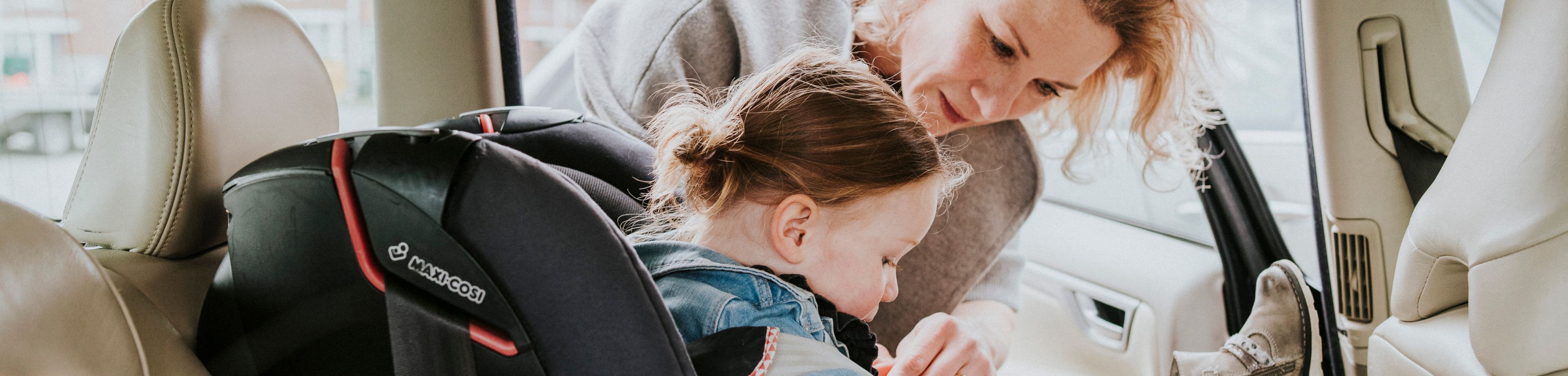 Een vrouw zet een meisje in haar autostoel