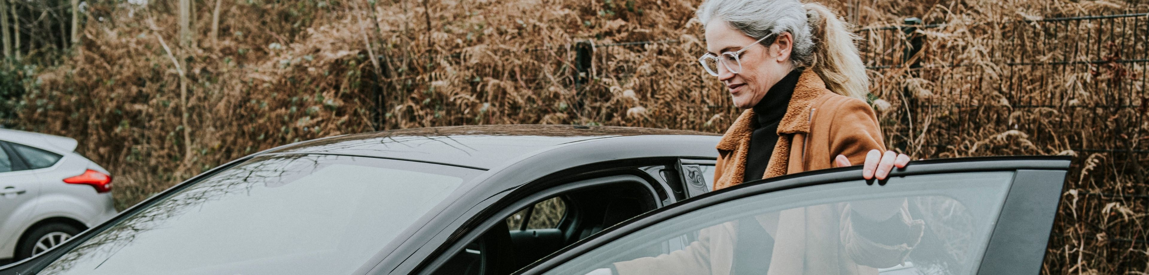 Vrouw stapt in de auto. Hoe voorkomt zij een verkeersboete?