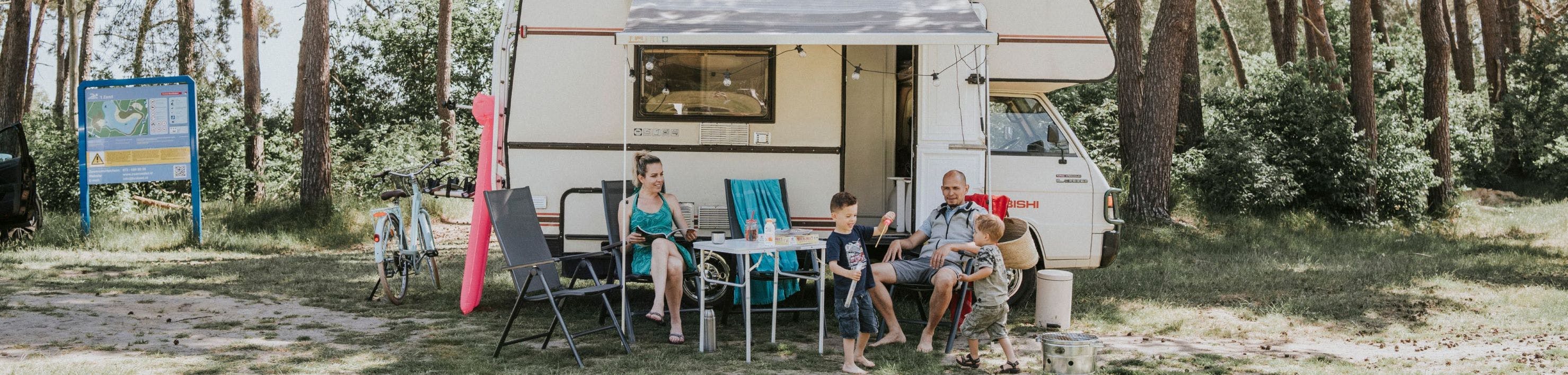 Een gezin zit voor de camper
