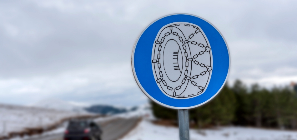 Een rond, blauw verkeersbord met een witte afbeelding van een autoband met sneeuwkettingen.